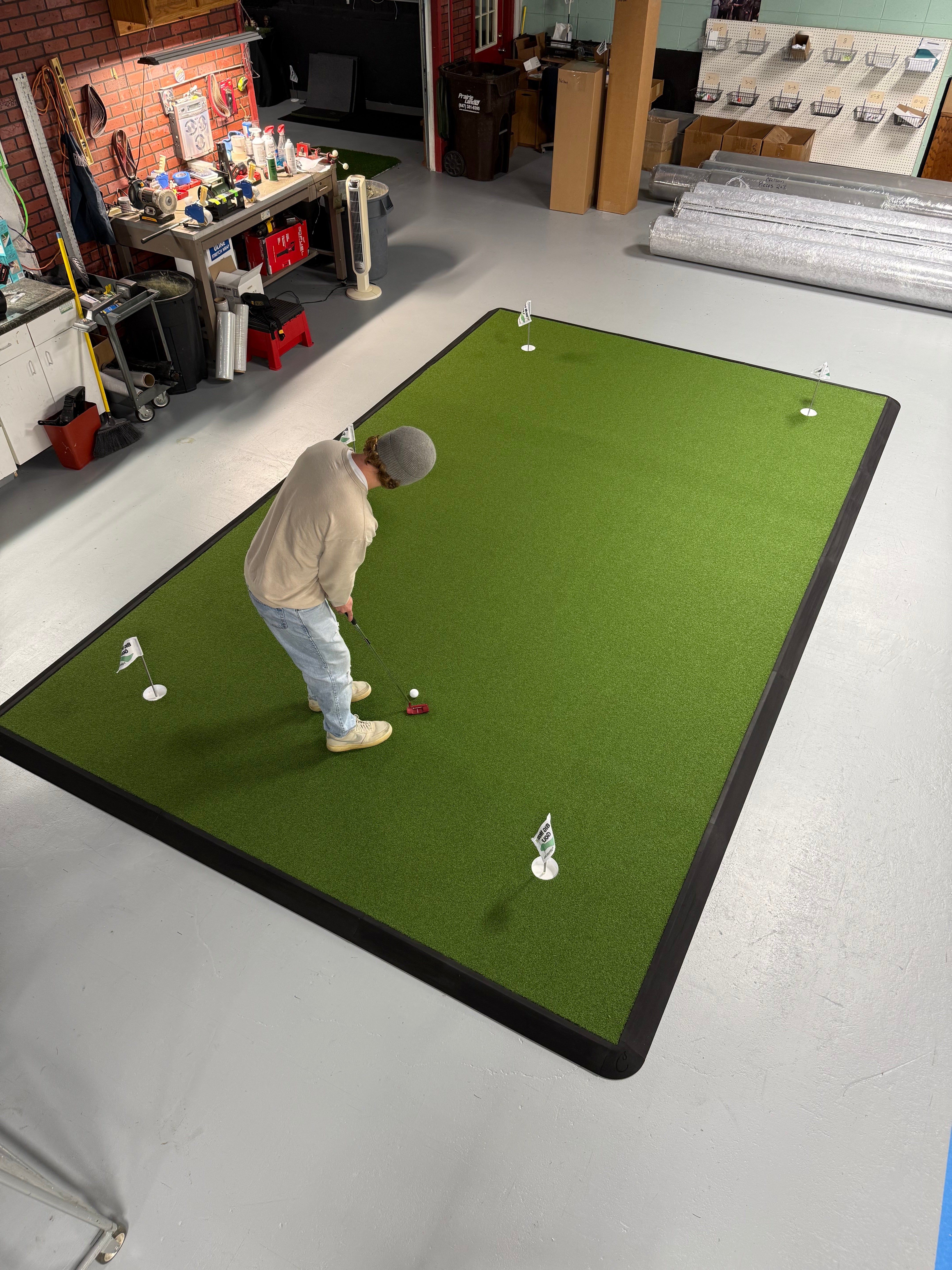 Person practicing golf on a putting green mat in an office