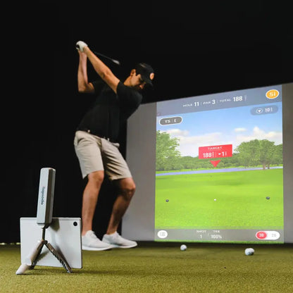 Rapsodo MLM2PRO launch monitor on its tripod behind a golf ball on a hitting mat, with a smartphone showing the Rapsodo app
